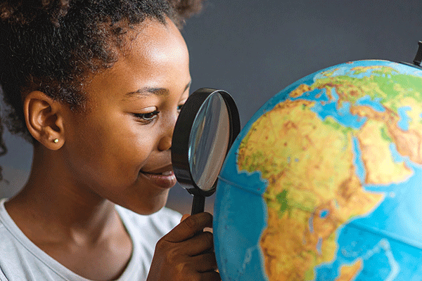 Vue-de-profil-une-petite-fille-regarde-le-continent-africain-à-travers-une-loupe-sur-un-globe